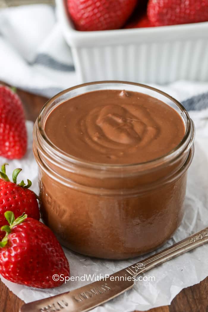 Homemade Nutella in a mason jar with strawberries on the side