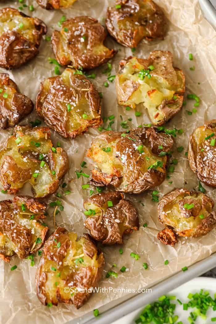 Roasted smashed potatoes on a baking sheet with chives