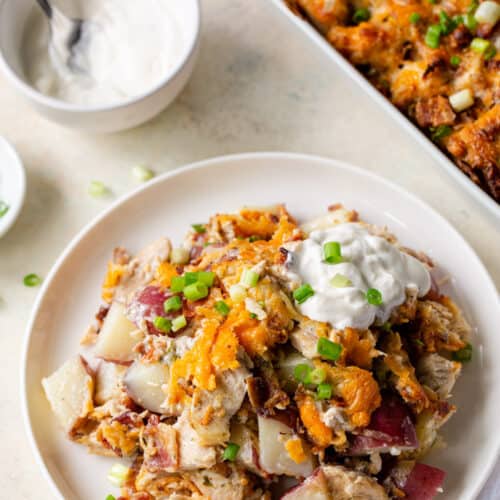 a plate of casserole with sour cream in the background