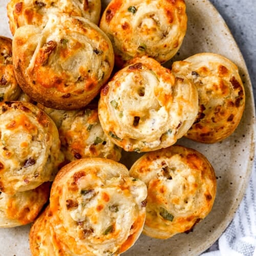 bacon cheese bites on a plate next to a white kitchen towel