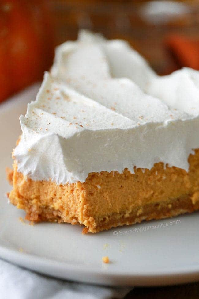 Slice of pumpkin cheesecake on a white plate with a bite taken out of it