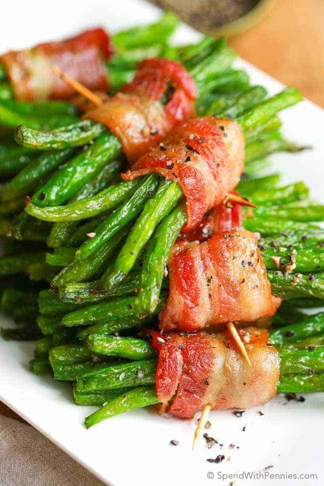 a stack of bacon wrapped green bean bundles on a white plate