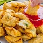 crab rangoon on plate being dipped in sauce