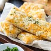 Best Cheesy Breadsticks on parchment paper with parsley