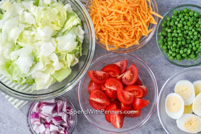 Ingredients for the perfect layered salad in bowls on a marble board