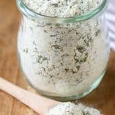 Clear jar of Ranch Seasoning Mix with spoonful laying next to it