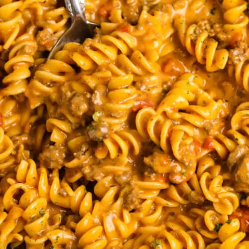 Cheesy taco rotini in a skillet with a serving spoon