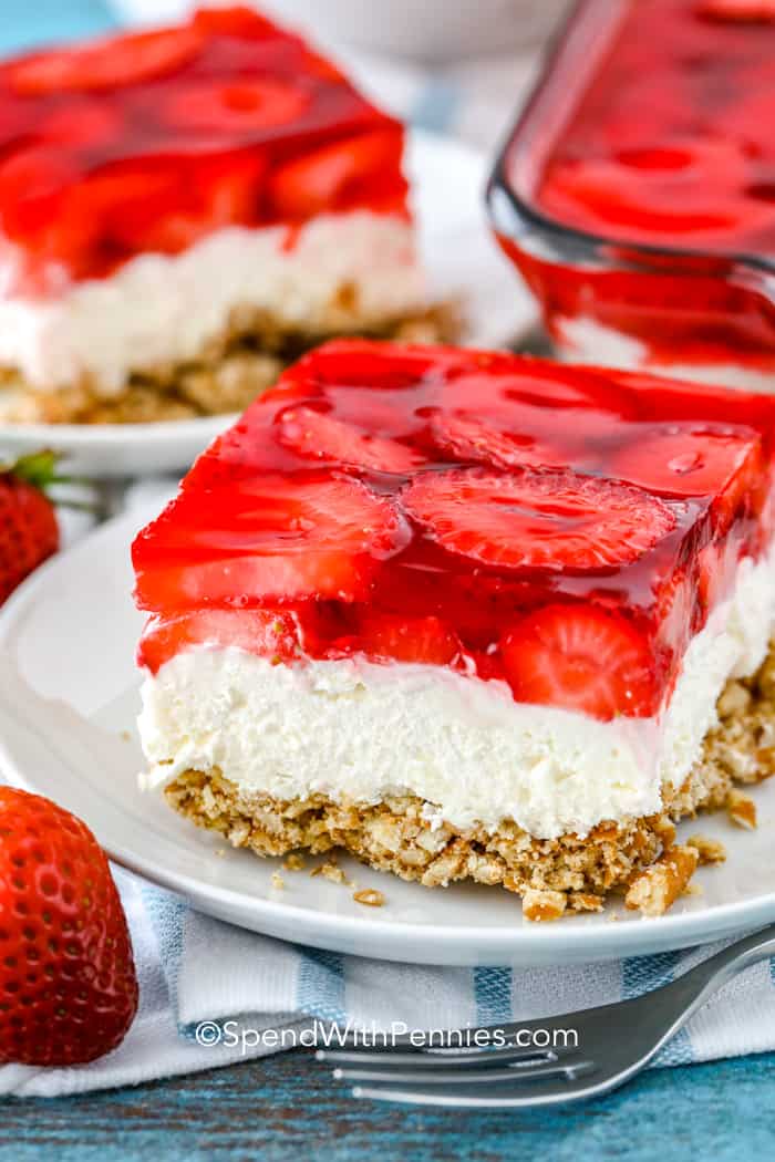Strawberry Pretzel Salad is the ideal dish for potlucks and parties! This easy dessert is packed with fresh fruit, jello, a creamy layer, and a buttery pretzel crust. Cut it into squares to serve a crowd for a potluck, party, or backyard barbecue! #spendwithpennies Strawberry Pretzel Salad served on a plate