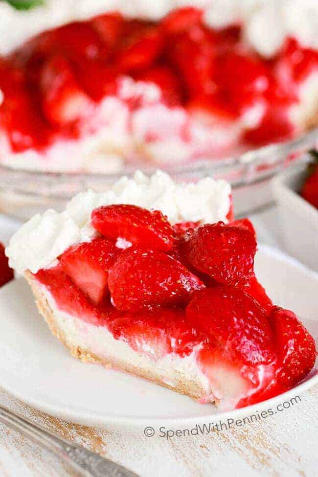 Piece of Strawberry Cheesecake Pie on a plate with a whole pie in a baking dish behind it