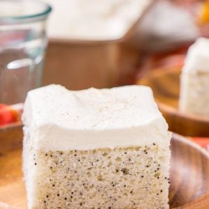 Almond Poppyseed Sheet Cake with frosting on a wood plate