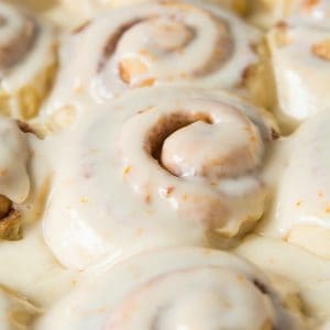 frosted orange cinnamon rolls with frosting on top in a pan