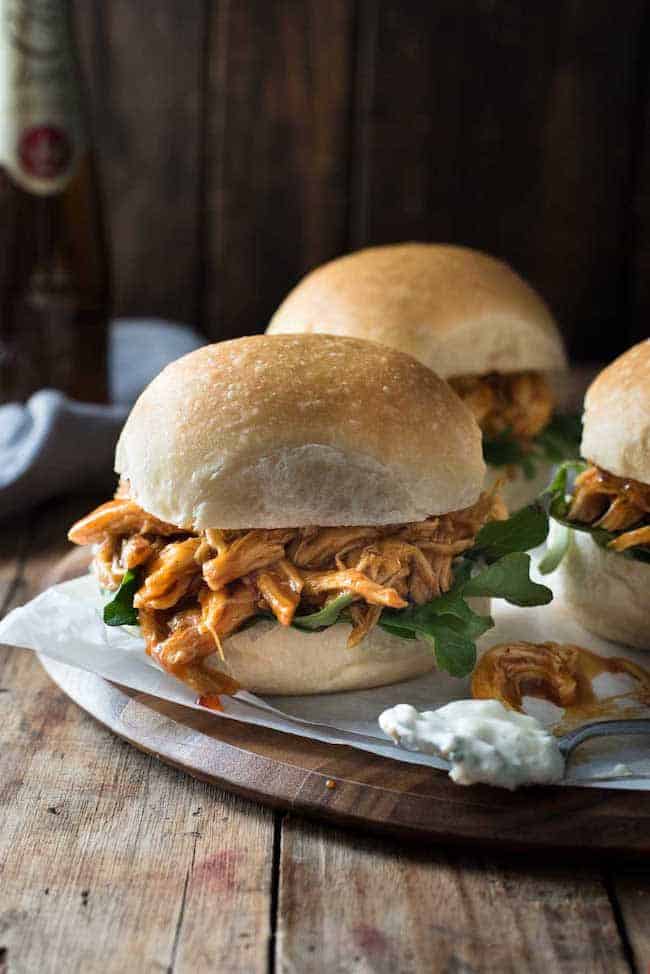 honey buffalo chicken sliders in buns on a wooden plate
