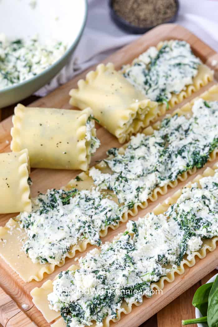 Rolled and unrolled lasagna on a cutting board with mixture