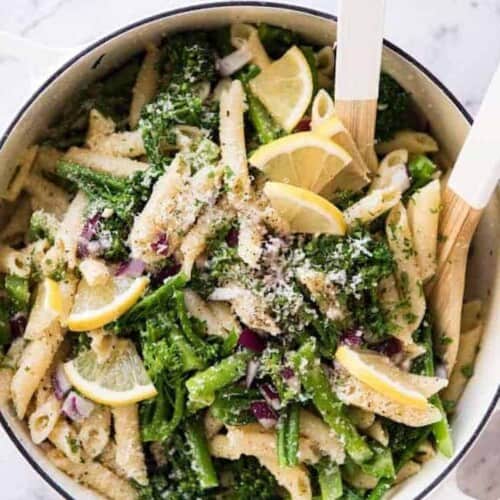 a bowl of penne pasta salad with broccoli and lemons