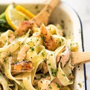 Lemon Butter Salmon Pasta in a baking dish with two wooden spoons