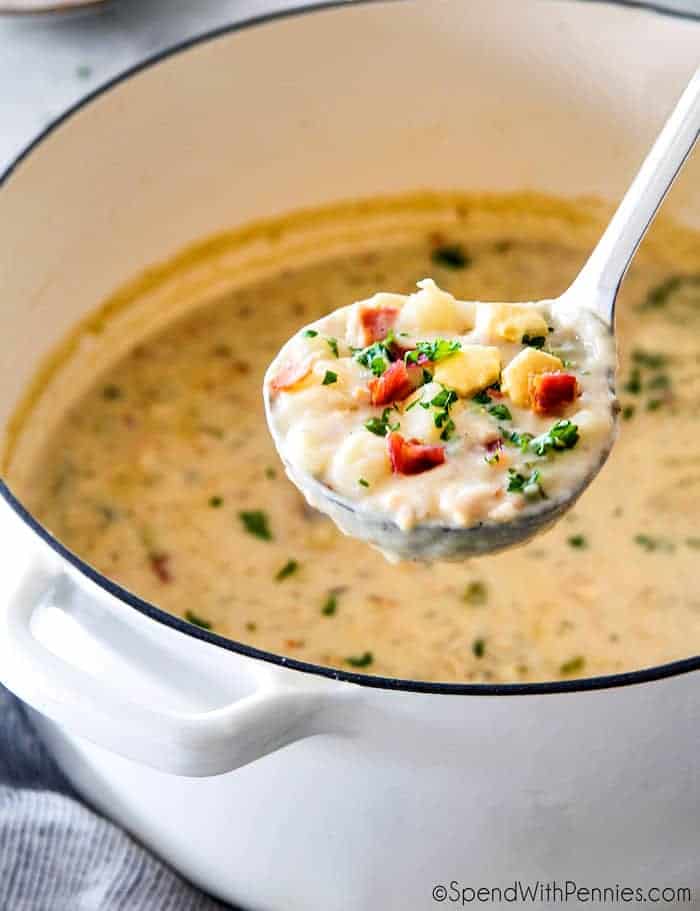 New England clam chowder in a ladle with a pot