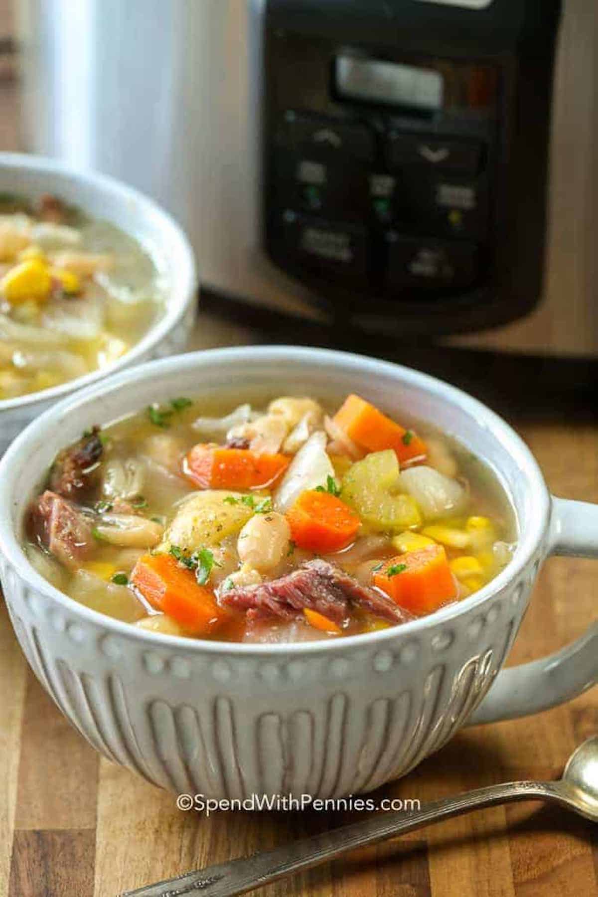 This ham bone soup recipe is easily made in the slow cooker, meaning you don't have any extra work to do after the holidays. It's an easy and delicious way to use up leftover holiday ham. Combined with beans, potatoes, and fresh veggies this simple slow cooker recipe is hearty and delicious. Just add dinner rolls for a meal everyone will love! #spendwithpennies #hambonesoup #slowcooker #leftoverham a bowl of ham bone soup