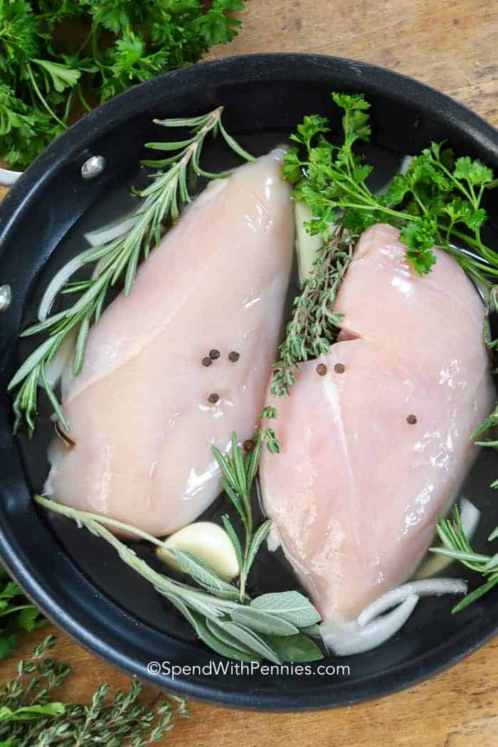 Raw Poached chicken in a pot with herbs