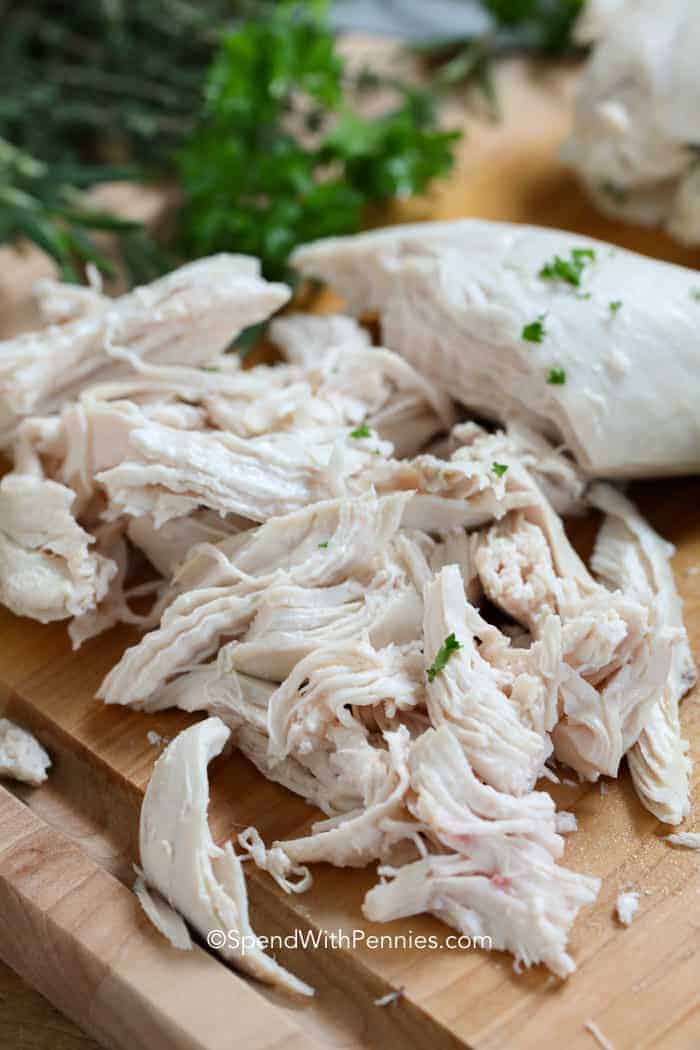 Shredded poached chicken on a wooden board