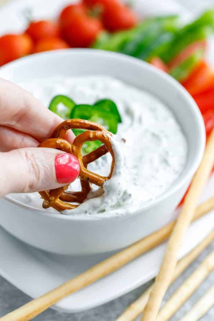 spicy dill dip in white bowl with pretzels