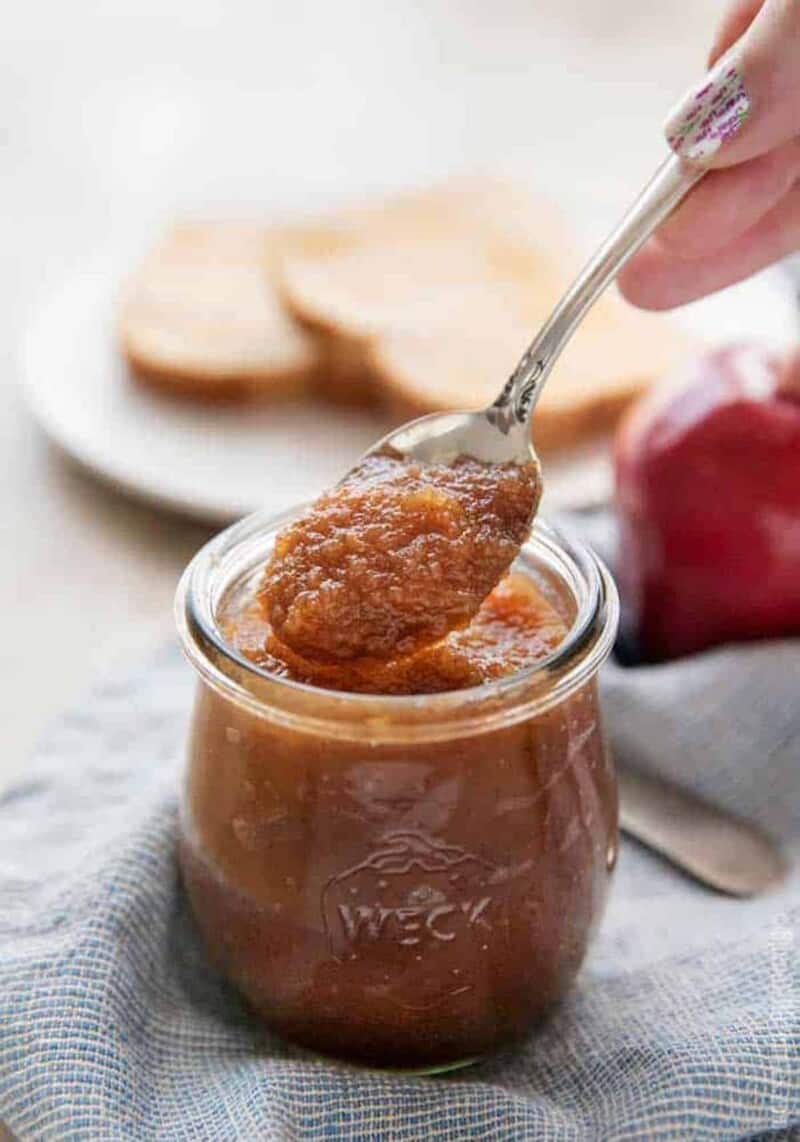 serving homemade apple butter with a spoon from a jar