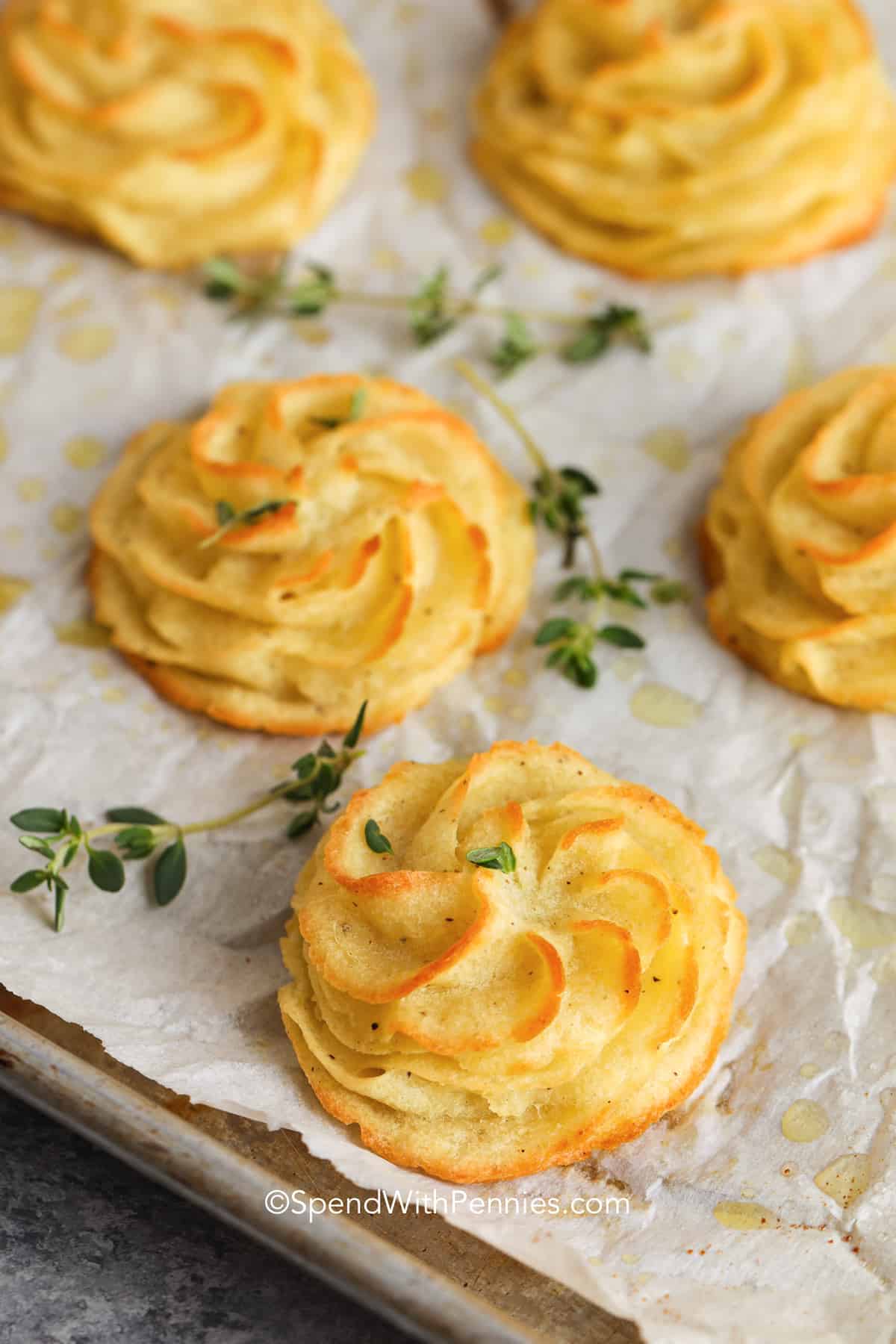 Turn those ho-hum mashed potatoes into these fancy duchess potatoes. These potatoes are such an impressive side dish to serve for guests and family alike. Make them ahead of time and pull them out to cook. Add a little cream cheese or some garlic and these potatoes are sure to impress. #duchesspotatoes #easyduchesspotatoes #duchesspotatoesrecipe #spendwithpennies duchess potatoes with herbs on a pan