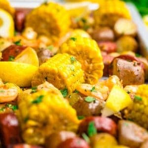 Shrimp boil on a sheet pan with corn, potatoes, shrimp, sausage, parsley, lemon wedges