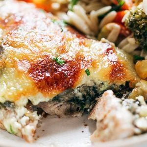 Closeup of a sliced piece of spinach artichoke chicken on a plate with salad
