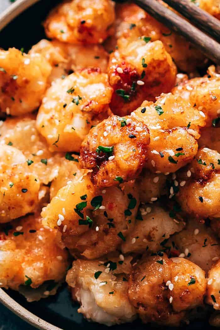 Closeup of bang bang shrimp coated in a spicy sauce topped with sesame seeds