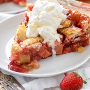 Strawberry Rhubarb Pie on a white plate with vanilla ice cream on top