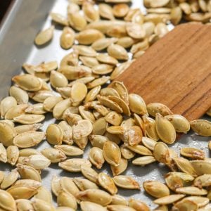 Using a wooden spatula to lift out Roasted Pumpkin Seeds from a baking sheet