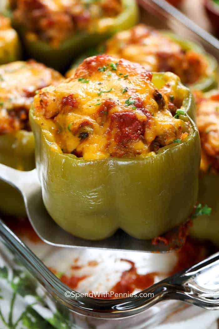 Stuffed peppers are a delicious combination of bell peppers filled with flavorful ingredients like seasoned meat, rice, and vegetables, creating a mouthwatering taste experience. This is a complete meal in one dish, perfect for a quick weeknight dinner. #stuffedpeppers #easy #recipe #spendwithpennies Stuffed Pepper being lifted out of baking dish