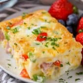 Piece of Denver Egg Casserole on a plate with strawberries and blueberries