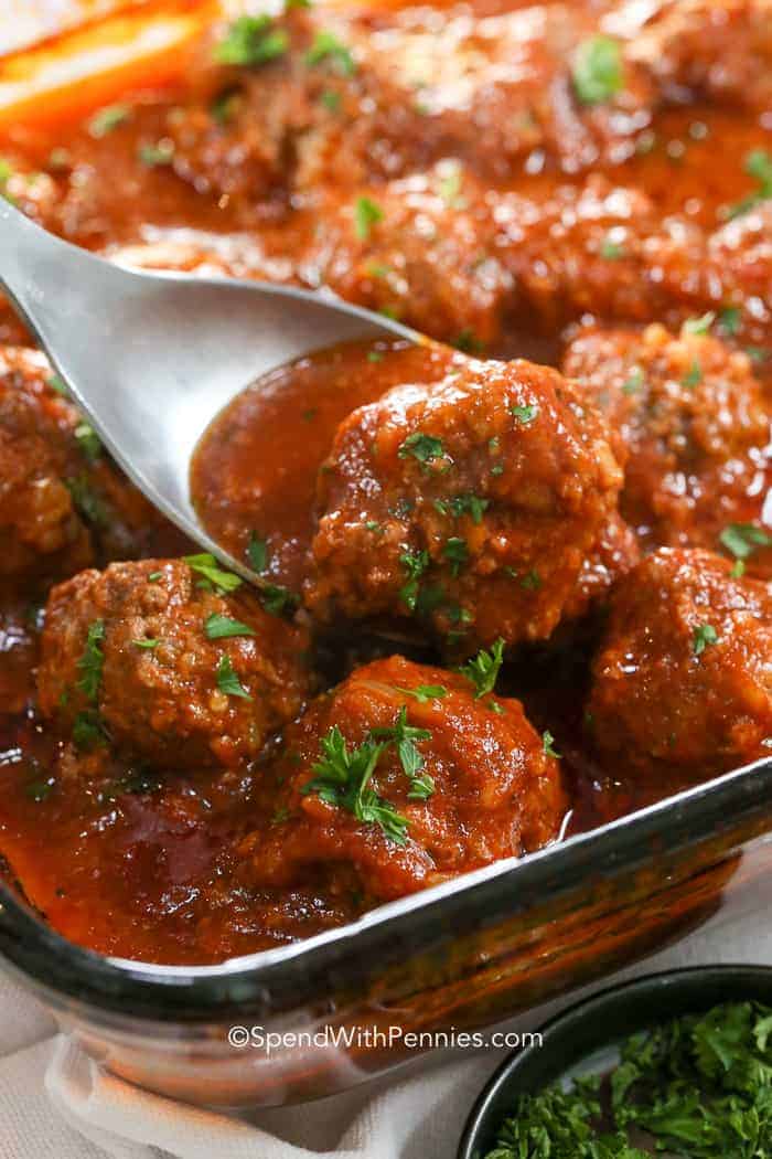 A porcupine meatball is just like a regular meatball, only with rice added to it. Cooked in a flavorful tomato sauce, these meatballs are tender and juicy. They are so good served over noodles, or potatoes. #spendwithpennies Porcupine Meatball being lifted out of baking dish