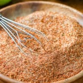 Fajita seasoning in a wooden bowl with limes in the background