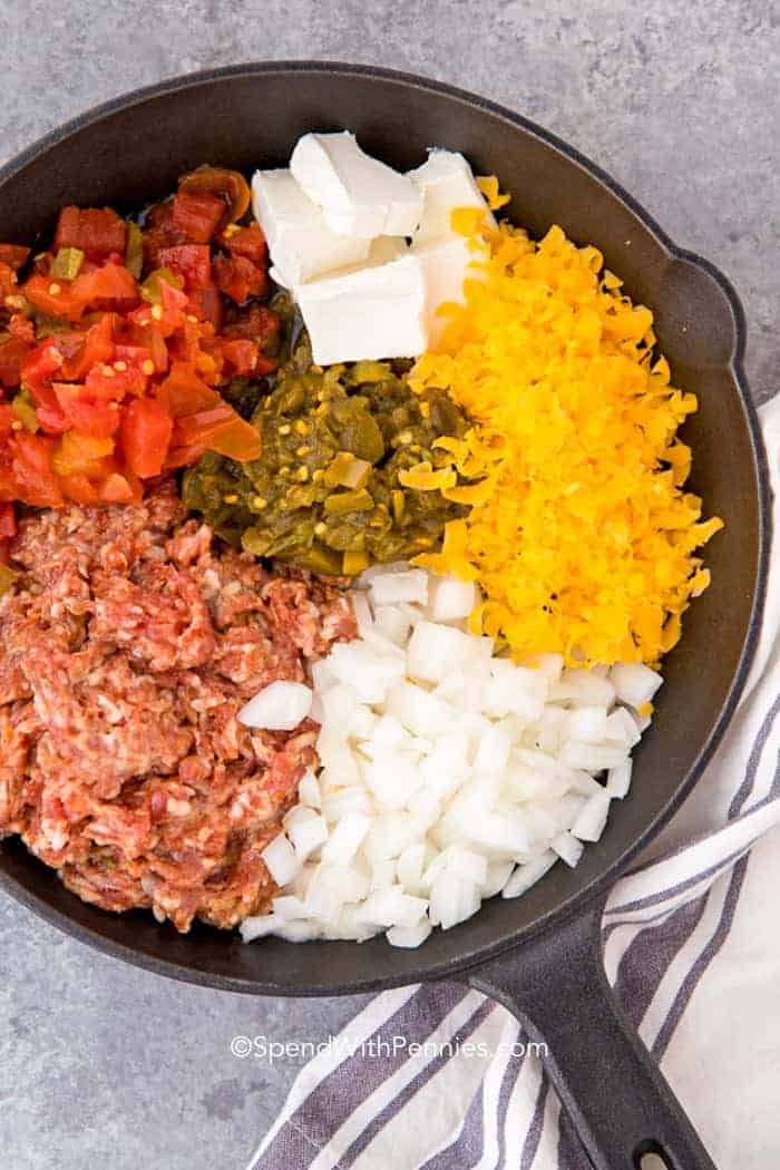 Sausage Queso Dip ingredients in a black pan before mixing together