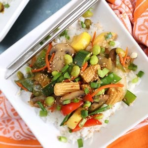 Overhead shot of Stir Fry Veggies served over rice on a square white p late