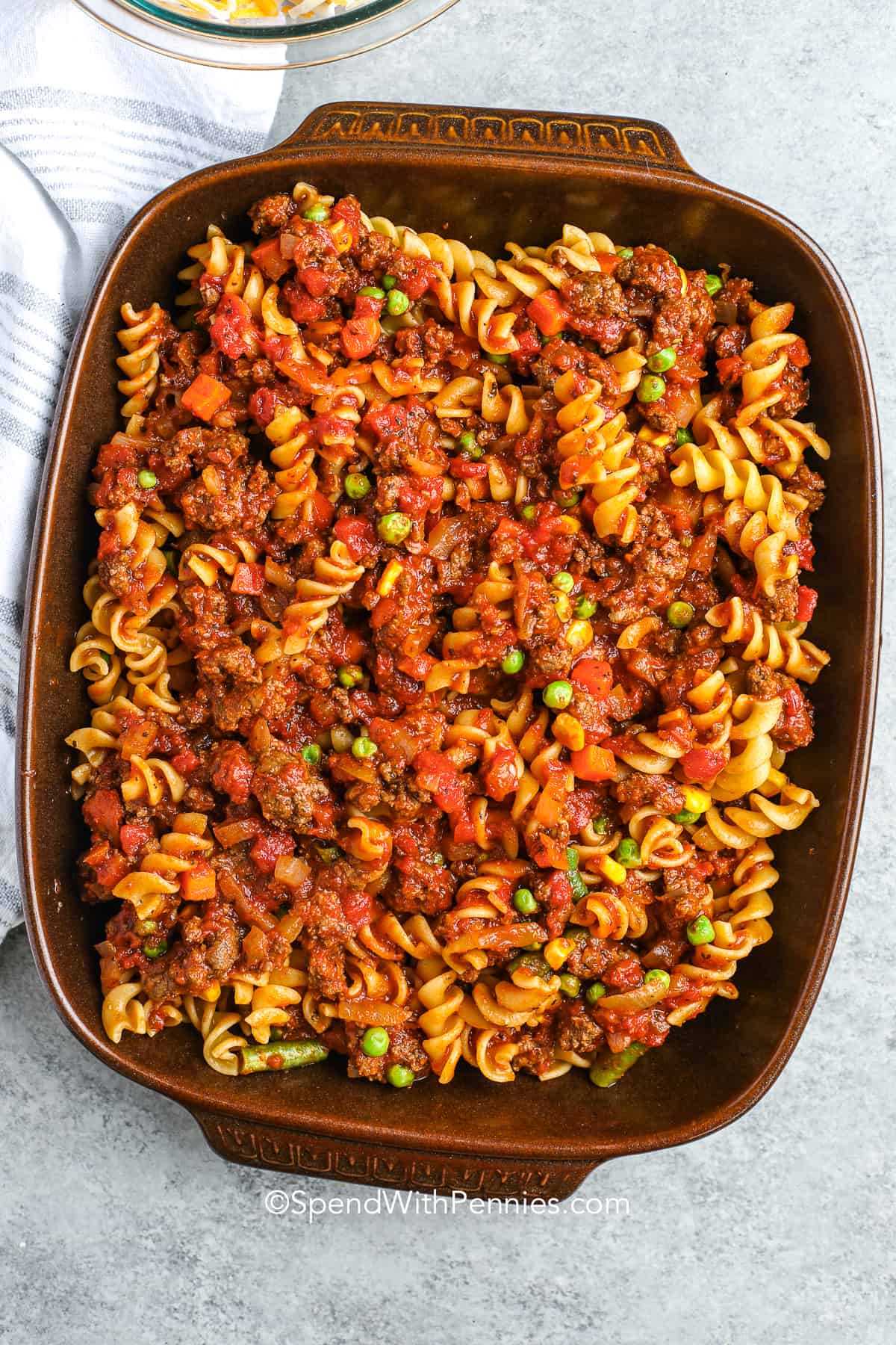 Hamburger casserole is an excellent recipe when you want comfort food without fuss. Though not a soup or bean dish, it delivers in flavor thanks to tomato sauce, ground beef, and plenty of cheese. You could add mushroom slices or a splash of cream for extra depth, or even stir in rice or noodles. It’s warm, cheesy, and very easy to adapt. #spendwithpennies mixed sauce, noodles and vegetables in a casserole dish for hamburger casserole