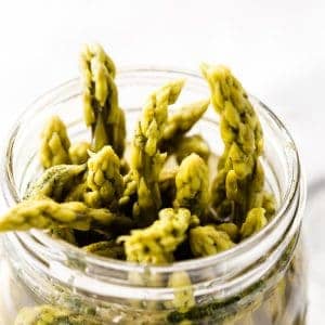 The tops of pickled asparagus peeking out of a canning jar