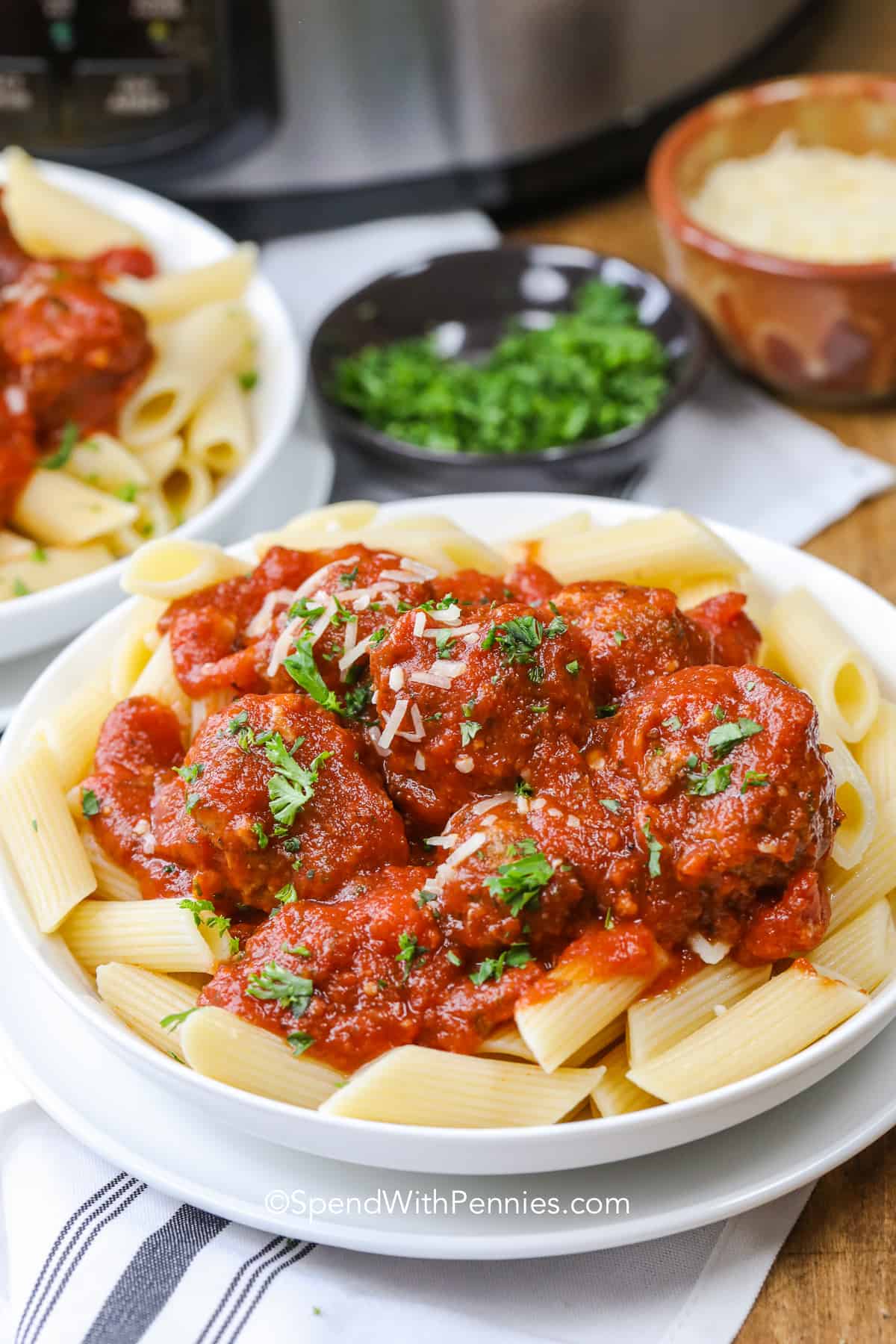 Tender homemade crockpot meatballs simmer in tomato sauce while the slow cooker handles almost all of the work. Ground beef, Italian breadcrumbs, Parmesan, parsley, and seasoning give every meatball plenty of savory flavor, while jarred marinara keeps prep quick. Serve the meatballs and sauce over spaghetti or turn leftovers into cheesy subs the next day. Save this meatballs recipe for an easy, cozy dinner. #spendwithpennies crock pot meatballs over pasta in a bowl with parsley