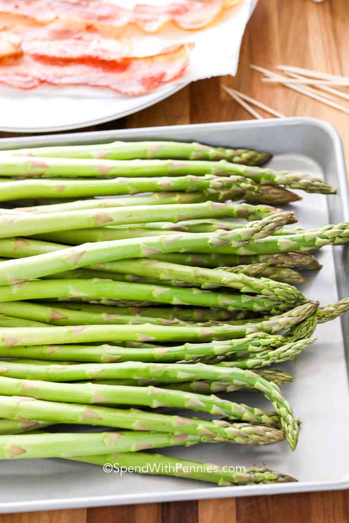 A tasty bacon-wrapped asparagus recipe is one of the best side dish recipes. This impressive dish is so easy to make. Simply make bundles of asparagus, wrap them in bacon, and then roast. So simple, so tasty, so crispy, and so good! #baconwrappedasparagus #baconwrappedasparagusintheoven #baconwrappedasparagusrecipe #spendwithpennies plain Asparagus with bacon in the background