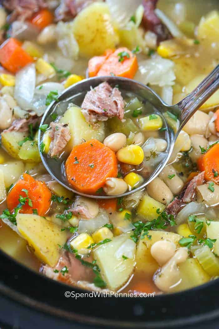 This easy ham bone soup recipe is one of our favorites. It combines leftover Christmas ham with delicious veggies to give you the perfect slow cooker soup! Let it simmer away while the yummy smell of supper fills your house. Serve with your favorite biscuits for dipping to create a meal everyone will enjoy. #spendwithpennies #hambonesoup #slowcooker #leftoverham ham bone soup in dish being served