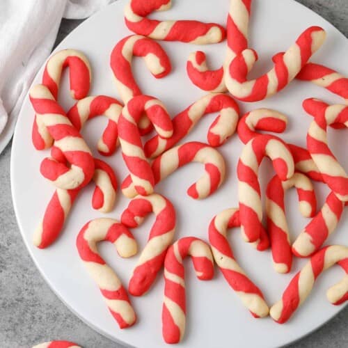 scattered baked candy cane cookies on a white plate