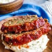 Two slices of crockpot meatloaf on plate with mashed potatoes