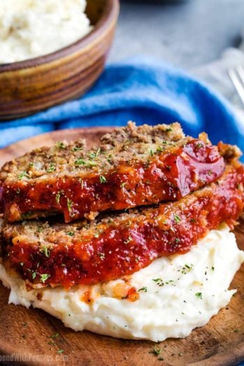 Two slices of crockpot meatloaf on plate with mashed potatoes