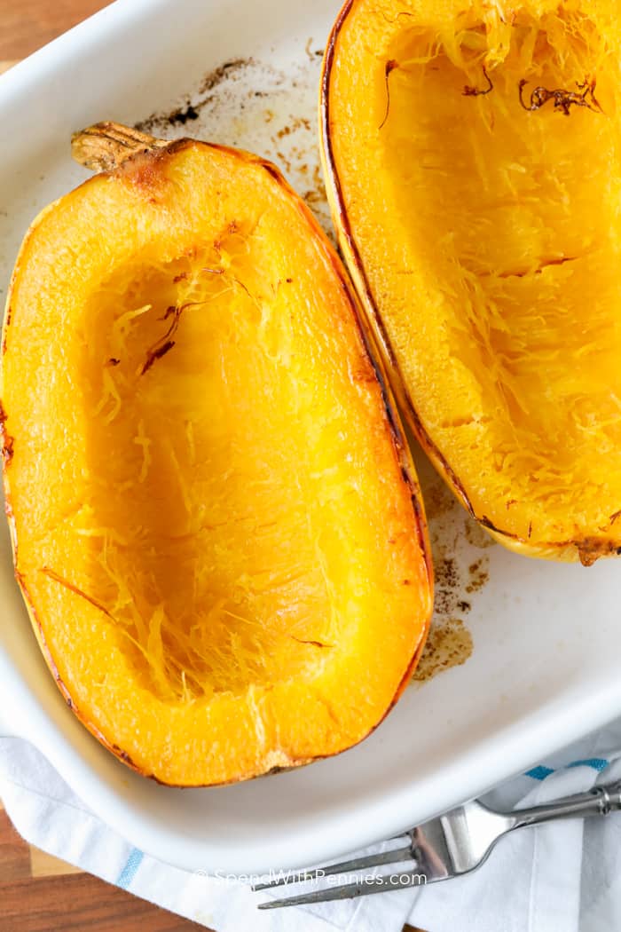 Baked spaghetti squash is a tasty pasta alternative that's healthier and simple to whip up. Just pop it in the oven to unlock its natural sweetness, and you've got yourself a low-carb noodle substitute. Whether you go classic with sauce, herbs, and cheese, or get imaginative with stir-fries, it's sure to be a delicious meal! #bakedspaghettisquash #lowcarb #baked #spendwithpennies two halves of Baked Spaghetti Squash in a dish
