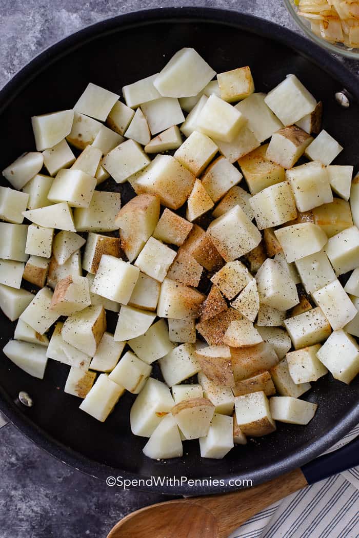 Uncooked potatoes in a pan with seasonings