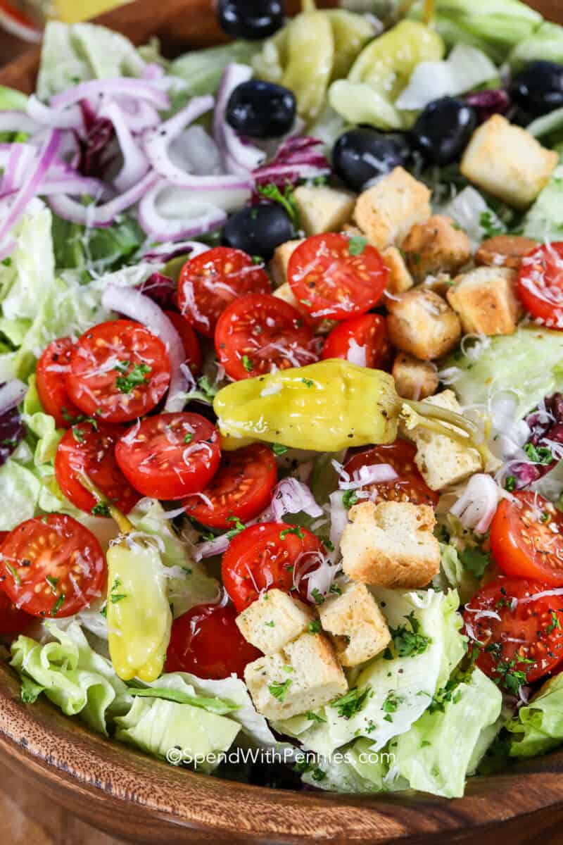 This Italian salad is the freshest salad recipe ever. We love serving it alongside Italian main dishes like chicken parmesan. Or make it a tasty lunch by adding chicken or shrimp! #spendwithpennies #italiansalad #salad #easysalad A close up photo of an Italian salad with parmesan cheese