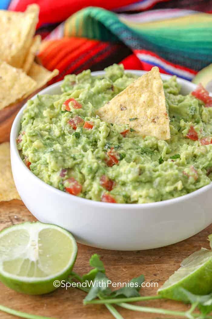 Homemade guacamole in a bowl with avocados and cilantro