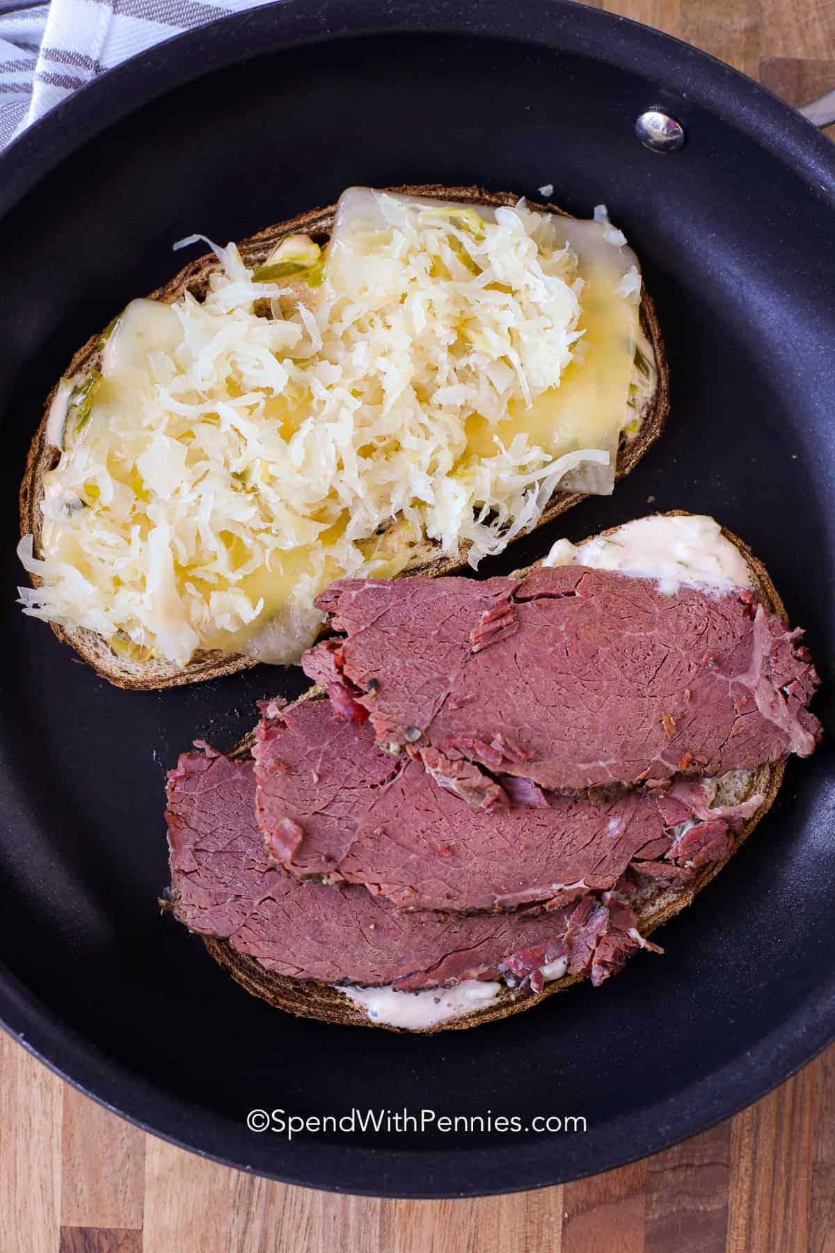These homemade Reuben sandwiches are an easy and delicious homemade sandwich recipe that is perfect to use up leftover corned beef. We love making these Reuben sandwiches for lunch or dinner on St. Patrick’s Day or any day! #reubensandwich #sandwich #reuben #spendwithpennies open faced reuben sandwich in a frying pan